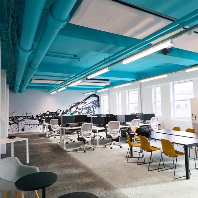 Office interior with exposed ceiling ductwork where the Artica system is installed