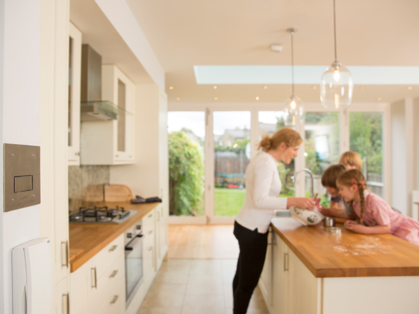 Plumis wall unit beside a kitchen where a family is baking