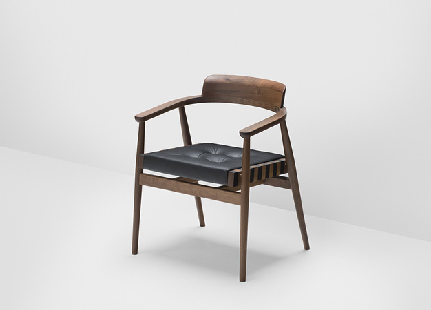 Hayche armchair with curved wooden arms and a black leather seat cushion