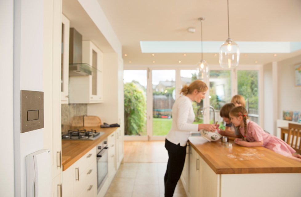Plumis wall unit beside a kitchen where a family is baking