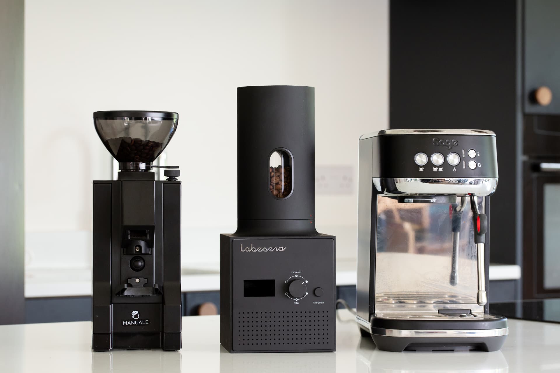 Labesera roaster on a kitchen counter between a coffee grinder and an espresso machine