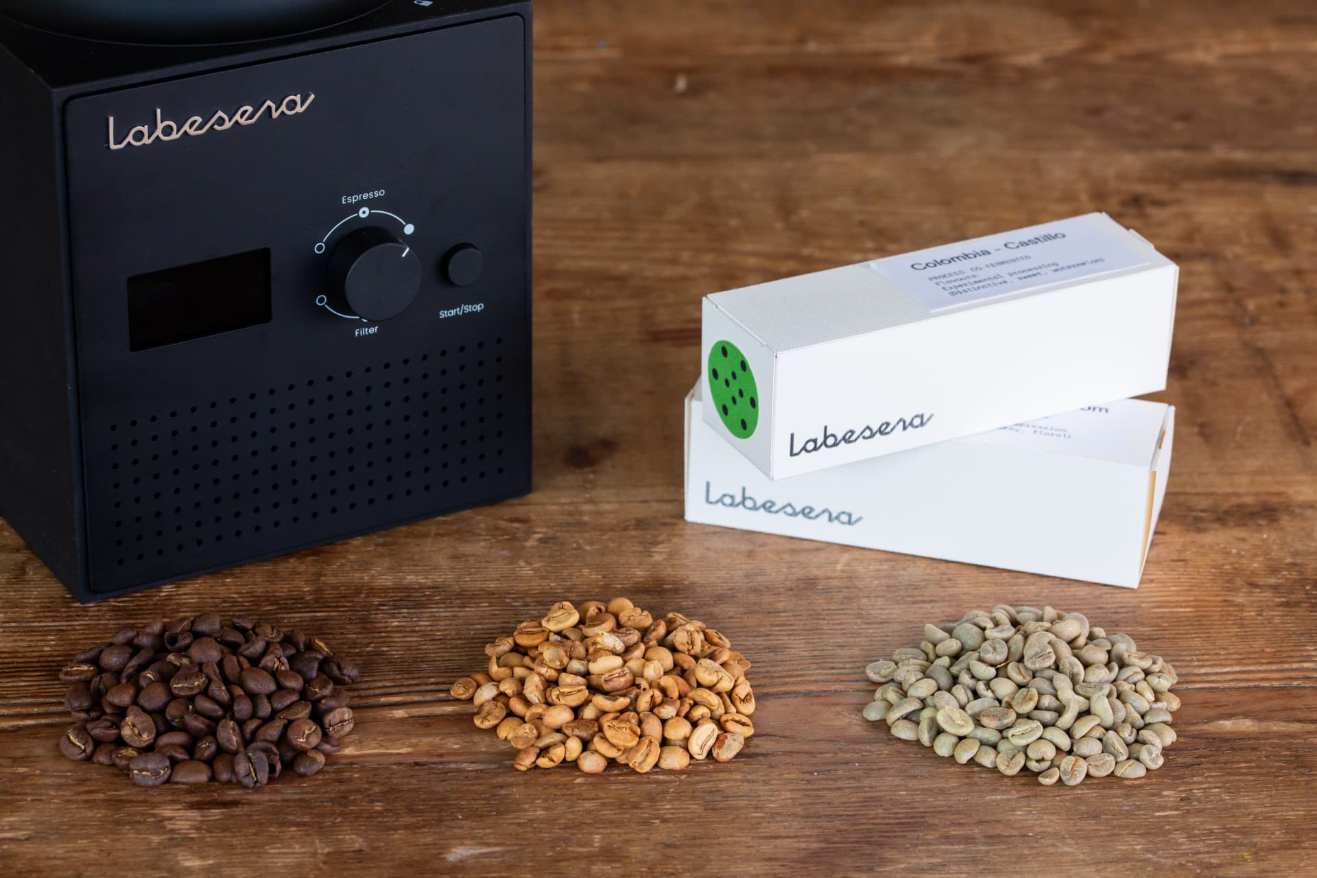 Labesera control panel with screen, espresso to filter dial and start button, beside pouches and dark, light and green coffee beans